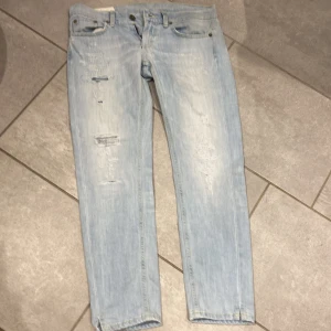 Ljusblå jeans från Dondup - Säljer ett par ljusblå jeans från Dondup med slitna detaljer och en straight passform. 