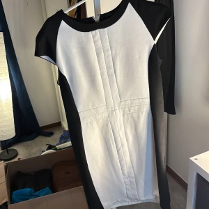 Svart och vit klänning från Zara Basic - Snygg svart och vit klänning från Zara Basic med korta ärmar och en stilren design. Klänningen har en dragkedja i ryggen och är perfekt för en elegant look.