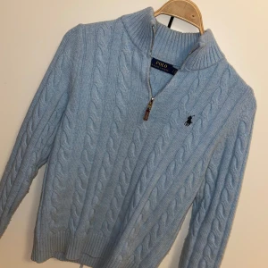 Ljusblå stickad tröja från Ralph Lauren - Säljer en stilren ljusblå stickad tröja från Ralph Lauren med kabelstickat mönster och dragkedja vid halsen. Tröjan har en broderad logotyp på bröstet och ribbade kanter. Skriv gärna vid övriga frågor! OBS! Är utomlands mellan 21 dec - 4 jan, så kan skicka om beställningen sker senast 20:e, efter det tidigast 5 jan.