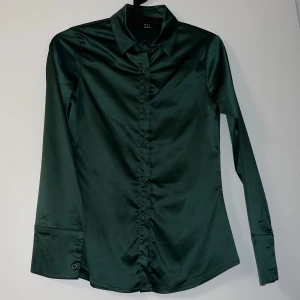 Grön satinblus från Shein - Elegant grön satinblus från Shein med långa ärmar och knappar framtill. Perfekt för en stilren look.