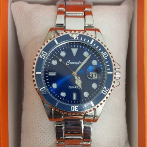 Blå klocka från Comuda - Snygg blå klocka från Comuda med silverfärgad länk och tydliga markeringar. Utrustad med datumvisning och kvartsurverk. Perfekt för en stilren look.