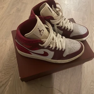 Nike Air Jordans i vinrött och vitt - Snygga Nike Air Jordans i vinrött och vitt med klassisk snörning. Perfekta för dig som vill ha en stilren och sportig look. Skorna har en ikonisk design med Jumpman-loggan på plösen.