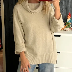 Krämvit tröja med polokrage - Mysig krämvit stickad tröja med en bred polokrage och långa ärmar. Perfekt för kyliga dagar med sin avslappnade passform och ribbade detaljer vid ärmslut och nederkant. Jag är i vanliga fall en S men köpte den i XL för en oversized fit.💕