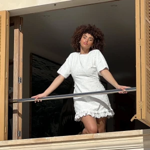 Vit kortklänning med blommor  - Perfekt vit kortklänning till student m.m med broderade blommor och volangdetaljer vid fållen. Klänningen har korta ärmar och en öppen rygg. (Armarna är uppsydda en bit)  