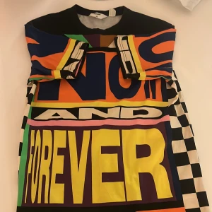 Säljer en färgglad tröja från H&M. Jag väljer att sälja denna tröjan eftersom jag har växt ut den. - Säljer en färgglad klänning med stora bokstäver och texten 'NOW AND FOREVER'. Klänningen har ett mönster med ränder och block i olika färger som orange, gul, blå och rosa. Perfekt för den som vill sticka ut med en unik stil.