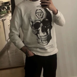 Vit tröja från Philipp Plein - Säljer en tröja från Philipp Plein med ett stort dödskalletryck på framsidan. Tröjan har långa ärmar och en rund halsringning. Storlek M. Fint skick. Bra i storlek. Skicka iväg ett meddelande vid mer info/bilder! 🌸 vid snabb affär kan jag tänka mig billigare.