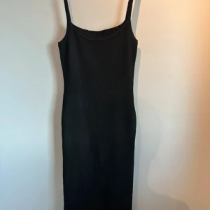Svart ribbad klänning - Snygg svart ribbad klänning med smala axelband och en figurnära passform. 
