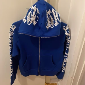 Blå hoodie med tryck - Snygg blå zip up  hoodie i storleken M och är köpt från ali express. Har använt den 2-3 gånger och är fortfarande i bra skick 