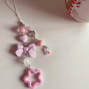 Rosa mobilhänge med stjärna och rosett🎀 - Handgjord mobil- eller nyckelring med söta detaljer i rosa och vitt. Perfekt som present eller accessoar! Designen innehåller en liten rosett, hjärtan, stjärna och en charmig liten figur. Lätt, stilren och unik💕