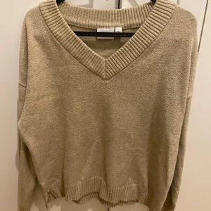 Beige tröja från VILA - Säljer en stilren beige tröja från VILA med v-ringad hals och ribbade detaljer vid hals och nederkant. Perfekt för en avslappnad look.