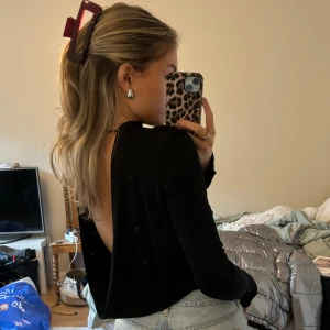 Svart långärmad topp med öppen rygg - Långärmad topp från zara med öppen rygg. Finns snöre i nacken som gör att den inte glider ner för axlarna! Nästintill ny, endast nevöns 1-2 gg. Osäker på storlek men tror 36/38