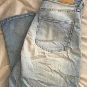 Ljusblå jeans från &Denim från H&M st 170 - Säljer ett par ljusblå jeans från &Denim i bra skick. De har en klassisk femficksdesign och är perfekta för vardagsbruk. Jeansen har en normal passform och är tillverkade i bomull, vilket gör dem både bekväma och hållbara. St 170. Super stretch heter modellen. Dottern hade dom fram till hon var 172cm lång. 