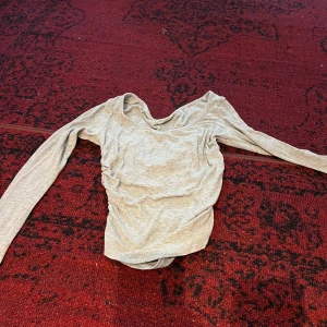 Beige långärmad topp - Säljer en snygg beige långärmad topp i mycket bra skick. Den har en draperad halsringning som ger en elegant touch. Perfekt för både vardag och fest! Passar bra till jeans eller kjol. Hör av dig vid intresse! 😊