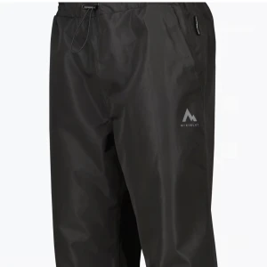Svarta regnbyxor från McKinley - Säljer ett par svarta regnbyxor från McKinley. De är perfekta för regniga dagar med sin vattentäta design. Byxorna har en elastisk midja med dragsko för justerbar passform och reflexdetaljer vid benen för extra synlighet. Perfekta för utomhusaktiviteter när vädret inte är på topp!