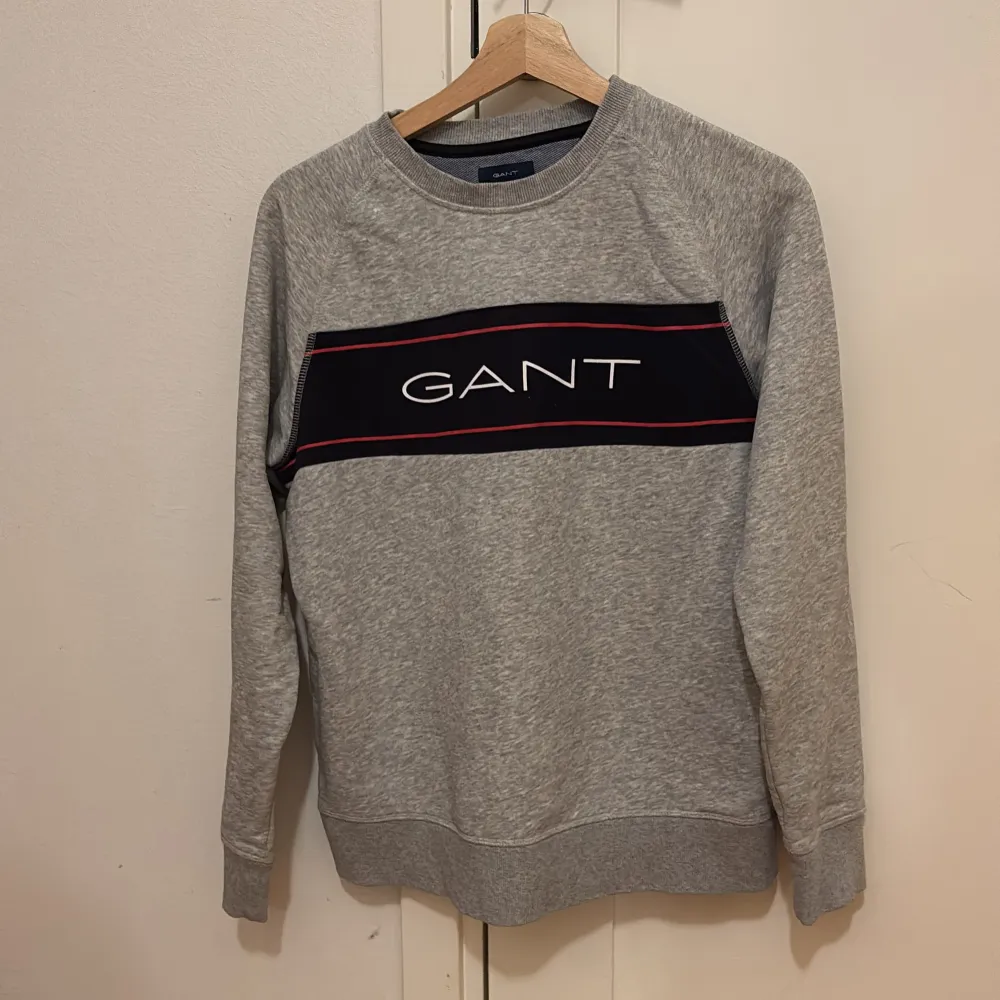 Säljer en snygg grå sweatshirt från GANT i mycket bra skick. Den har ett stilrent tryck med GANT-loggan i vitt och rött på bröstet. Perfekt för både vardag och chill. Nypris: 1200. Tröjor & Koftor.