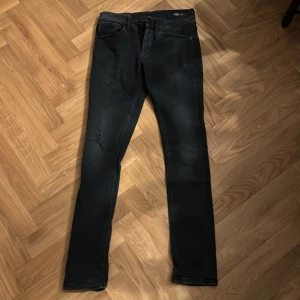 Svarta Dondup George jeans med slitningar  - Säljer ett par snygga svarta jeans från Dondup i bra skick. De har en slim passform och slitningar på framsidan, skriv vid intresse samt frågor, pris är ej hugget i sten😉