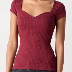 Vinröd ribbad topp från Anna Field - Snygg vinröd ribbad topp från Anna Field med en v-ringad design. Toppen har korta ärmar och en tight passform som framhäver figuren. Perfekt för både vardag och fest!