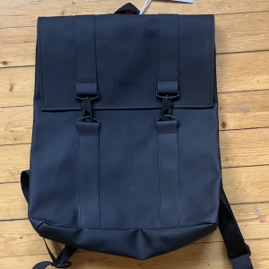 Mattsvart ryggsäck från Rains - Säljer en helt ny ryggsäck från Rains. Den är vattentät och därmed regntålig. Har även knappar på sidorna som gör det lätt att anpassa storlek efter vad du har i den. Ryggsäcken har ett lock med spännen och en stor innerficka där en dator passar perfekt! Nypris 799:-🌟 Mått och liknande finns på sista bilden.