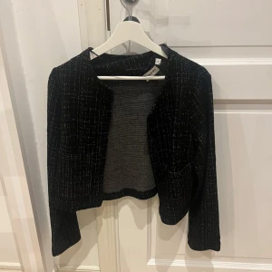 Svart rutmönstrad kofta - Säljer en snygg svart rutmönstrad kofta från kappahl som aldrig är använd. Den har en fin och stilren design med långa ärmar. Perfekt för både vardag och festliga tillfällen. Passar bra till höst och vår🩷