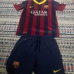 Äkta Barcelona 2013/ 2014 hemma kit - Säljer min Barcelona tröja från säsongen 2013/14 hemma kit storlek s i barn (137) med både tröja och shorts! Mycket bra skick. Perfekt att hänga upp på väggen eller till ett barn! Hör av dig vid frågor! Köparen står för frakten.