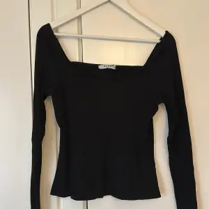 Säljer en snygg svart ribbad topp från NA-KD i storlek M. Toppen har en offshoulder-design med långa ärmar och en v-ringad hals. Perfekt för både vardag och fest! 🖤