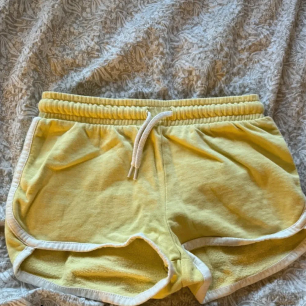 Säljer ett par supermysiga gula frottéshorts med vit kant och snörning i midjan. De har en loose passform och är i mycket bra skick. 🏖️❤️. Shorts.