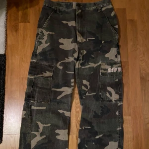 Camouflage cargobyxor - Säljer ett par coola camouflage cargobyxor. De har flera praktiska fickor och en loose fit som ger en avslappnad stil. Perfekta för en casual look eller utomhusaktiviteter. Custom flare. Priset kan diskuteras vid snabb affär😁👍