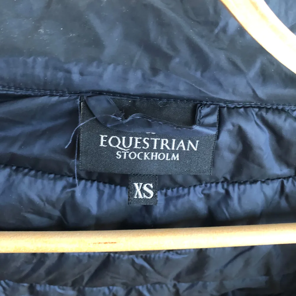 Säljer en snygg svart pufferjacka från Equestrian Stockholm i storlek XS. Jackan har en dragkedja framtill och två praktiska fickor med dragkedjor. Perfekt för kyliga dagar i stallet och har en design med broderad logga på ryggen. Har använt den vid ridning, bra skick.. Jackor.