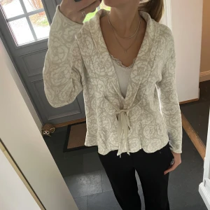 Beige stickad kofta med snörning  - Beige mönstrad kofta från Soda i storlek M, skulle säga att den även passar S. Fint skick. Använd gärna köp nu!