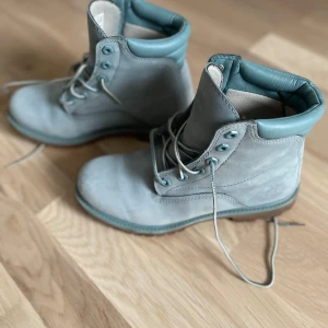 Blåa boots från Timberland - Säljer ett par gråa Timberland boots i bra skick. De är tillverkade i skinn och har en robust sula perfekt för höst och vinter. Skorna har snörning och är vattentäta, vilket gör dem idealiska för regniga dagar. Perfekta för en casual look eller en promenad i naturen.