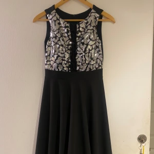 Cocktail klänning  - En svart knälång cocktail klänning med paljetter på bröstet.  Strl small.  Använd en nyår så helt ny. 