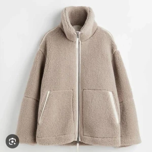 Beige teddyjacka med dragkedja - Supermysig beige teddyjacka med hög krage och dragkedja framtill. Perfekt för kyliga dagar med sina stora fickor och mjuka material. Jackan har en loose passform som gör den extra bekväm att bära. Ett måste för höst- och vintergarderoben!