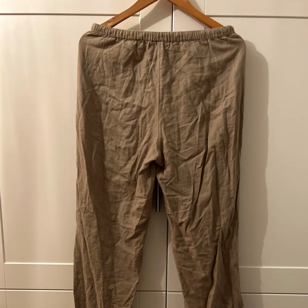 Säljer ett par bekväma beige linnebyxor i loose fit. Perfekta för sommardagar med sin lätta och luftiga känsla. Byxorna har en elastisk midja för extra komfort. Passar både till vardags lappande tillfällen. Använt ofta men i bra skick.🏖️. Jeans & Byxor.