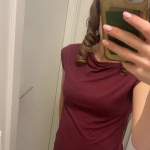 Vinröd topp - Säljer en stilren vinröd topp i mjukt material. Den har en enkel design med korta ärmar och en bekväm passform. Perfekt för både vardag och festliga tillfällen. Passar bra till jeans eller kjol! Aldrig använd så i super skick!!💕