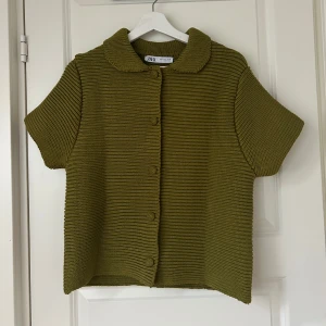 Olivgrön stickad kofta från Zara - Säljer en superfin olivgrön stickad kofta från Zara. Den har korta ärmar och knappar hela vägen fram. Perfekt för höst. Passar både till vardags och lite finare tillfällen. 🧶💚