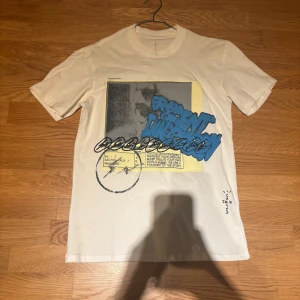 Travis scott t shirt - Travis scott fragment t shirt med ett coolt grafiskt tryck i blått och svart på framsidan. Nice puff print. Bara en liten fläck på ryggen som går att tvätta.