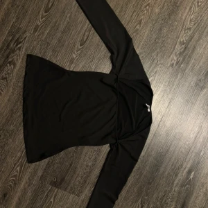 Svart långärmad topp från Nelly - Snygg svart långärmad topp från Nelly i en stilren design. Perfekt för en chic och enkel look. Toppen har en smickrande passform och är tillverkad i ett mjukt material.