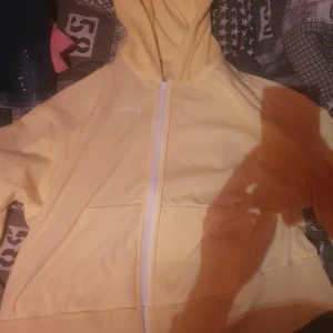 Gul huvtröja från Palm Angels - Säljer en gul huvtröja från Palm Angels med dragkedja och broderad logga. Perfekt för en avslappnad stil.