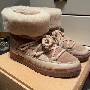 Beige boots från Inuikii - Säljer ett par snygga och varma beige boots från Inuikii. De har en mysig pälsdetalj runt skaftet och snörning framtill. Har använt men ändå bra skick! nypris 3,5 ish tryck inte på köp direkt:)