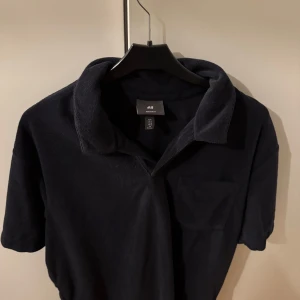 Frotté tröja navy blue från H&M - Säljer en stilren navy blue frotté tröja från H&M i regular fit. Tröjan har korta ärmar och en klassisk krage. Perfekt för en avslappnad men ändå snygg look perfekt på sommaren! Använd 2 gånger. 