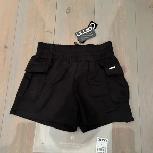 Svarta shorts från Aim'n - Snygga svarta shorts från Aim'n med elastisk midja och praktiska fickor med knappar. Perfekta för en aktiv livsstil. .Black comfy cargo shorts från Bianca Ingrossos boss babe collection med Aimn. Shortsen är nya med tags och skickas i sin original förpackning.  Storlek XS men är stora i storleken så passar även S.