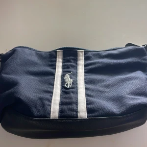 Blå Väska från Ralph Lauren - Säljer en fragrance bag från Ralph Lauren. Den är i mycket bra skick och har knappt använd. Man kan lägga smycken, smink, och annat! Passar också bra till att ha med på resa. Pris kan diskuteras! OBS: Varan har KNAPPT märke på användning.