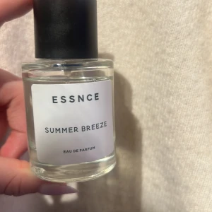 Essnce Summer Breeze Eau de Parfum - Fräsch och lätt parfym från Essnce med namnet Summer Breeze. Flaskan är genomskinlig med en enkel vit etikett och svart kork. Perfekt för en somrig känsla.