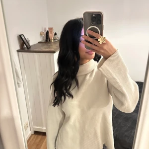 Vit ribbad polotröja - Säljer en stilren vit ribbad polotröja med långa ärmar. Perfekt för kyligare dagar och lätt att matcha med olika outfits. Tröjan har en avslappnad passform och är superbekväm att bära.