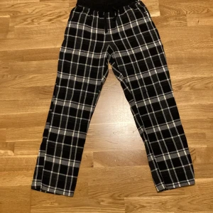 Svart- och vitrutiga byxor från Kappahl - Säljer ett par bekväma svart- och vitrutiga byxor från Kappahl. De har elastisk midja med snörning för extra komfort. Perfekta för en avslappnad stil.