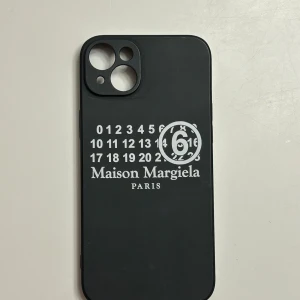 Svart mobilskal från Maison Margiela - Snyggt svart mobilskal från Maison Margiela med deras nummerdesign i vitt. Skalet är för 14 MAX men jag tror alla Max telefoner är lika stora, men om ni har några frågor om skalet så skriv gärna