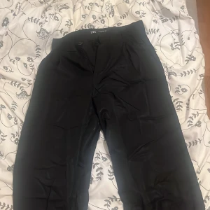 Svarta kostymbyxor från Zara - Snygga svarta kostymbyxor från Zara i storlek S. Byxorna har en klassisk design med dragkedja och knapp framtill. Perfekta för en stilren look. OBS- Kommer strykas innan skickning