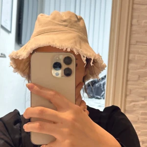 Beige hatt med fransar - Trendig beige hatt med fransiga kanter. Perfekt för en avslappnad stil och skydd mot solen. Hatten har en mjuk och bekväm passform.