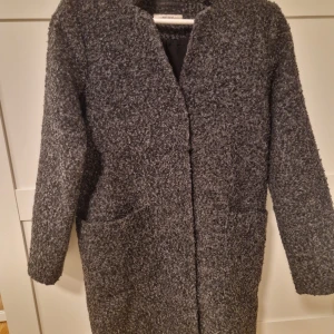 Grå ullblandad kappa från  gina tricot - Snygg grå kappa i ullblandning från Saint Tropez. Den har en stilren design med långa ärmar och praktiska fickor framtill. Perfekt för kyliga dagar och ger en elegant touch till din outfit.