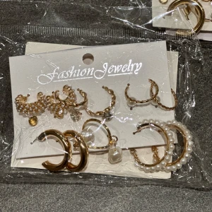 Set med guld- och pärlörhängen - Säljer ett set med örhängen i guld och pärlor. Setet innehåller flera olika stilar, inklusive hoops och små studs, perfekt för att mixa och matcha. Perfekt för att ge din look en elegant touch.